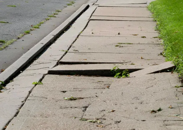 Damaged concrete sidewalk panels beside a curb