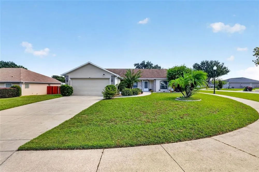 Concrete driveway leading to a single-story home beside a lawn