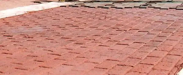 Red concrete stamped with a brick pattern beside a planted border